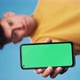 Man showing a smartphone with green screen while standing over an blue background. Slow motion - VideoHive Item for Sale