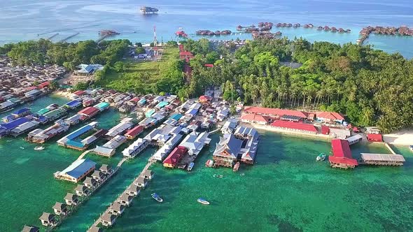 Aerial flight over local village and ocean in Malaysia, long shot perspective moving away in slow mo alt