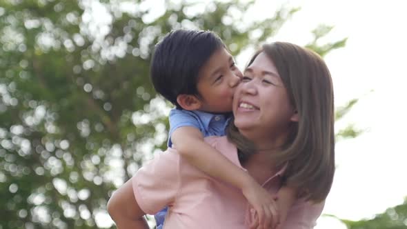 Asian Child On A Piggy Back Ride With Her Mother alt