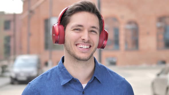 Outdoor Young Man Listening Music on Red Headphones alt