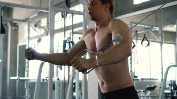 Shirtless Muscular Man Doing Cable Cross Over Chest Exercise at the Gym alt