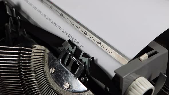 An old fashioned vintage typewriter spelling out the word Love multiple times alt