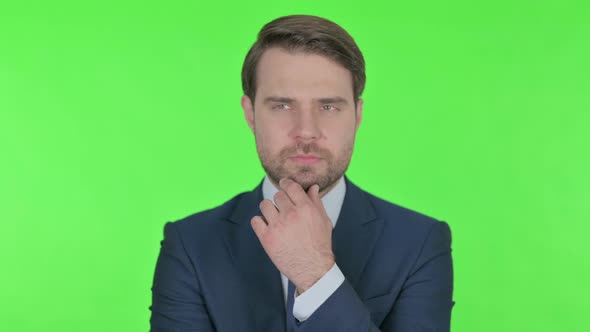 Pensive Young Businessman Thinking and getting Idea on Green Background alt