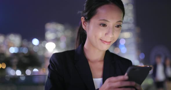 Woman Using cellphone with the background of Hong Kong city  alt