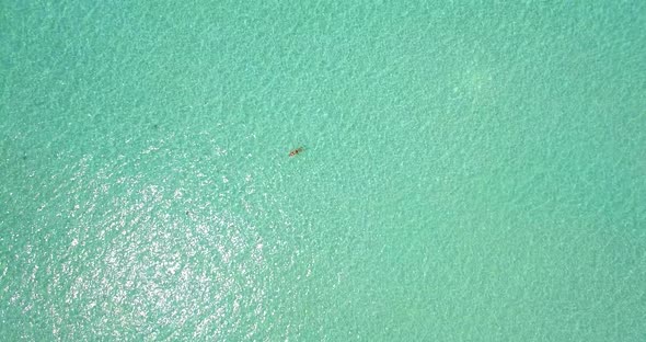 Aerial drone view of a woman floating and swimming on a tropical island. alt