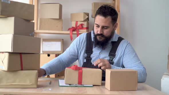 Hindu Male Business Owner Working From Home in Uniform with Packing Box at Workplace Online Buying alt