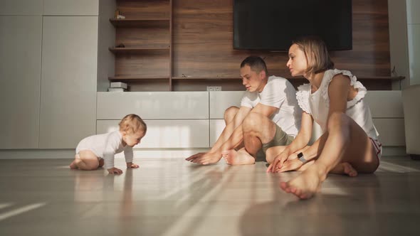 Cute Happy Little Toddler Baby Boy is Crawling to His Parents on a Wooden Floor at Home alt