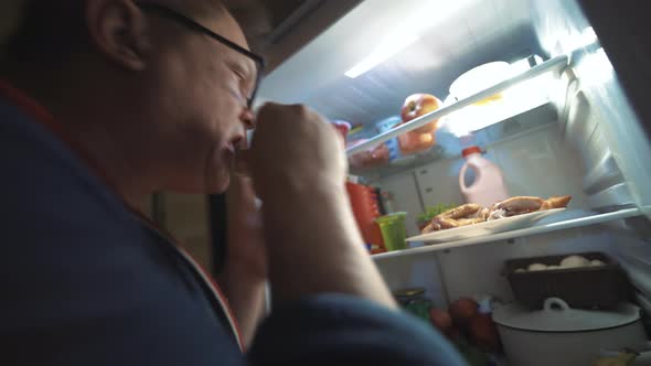 Adult Fat Man At Night Takes Food From The Refrigerator At Home And Eats Her alt
