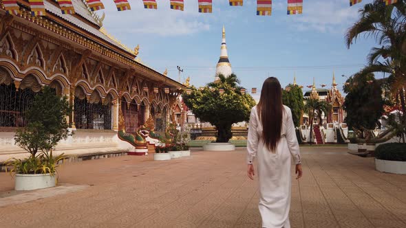 Young woman tourist walking in Buddhist Wat Luang Temple, Pakse, Laos. 4K Slow. Asian exotic culture