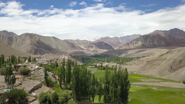 Establishing Aerial of Himalayan Mountain landscape in Ladakh, India. Green farm land below alt