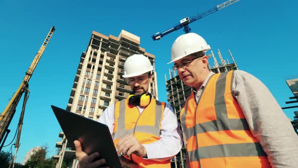 Working Engineers, Construction Architects Discussing Construction Plan Using Laptop While Standing alt
