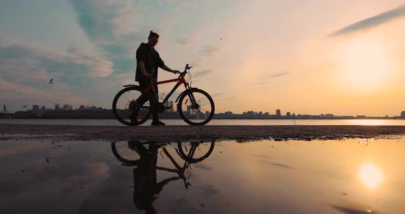 Silhouette of Bicyclist Sit Down Into His Bike at Sunset Slow Motion alt