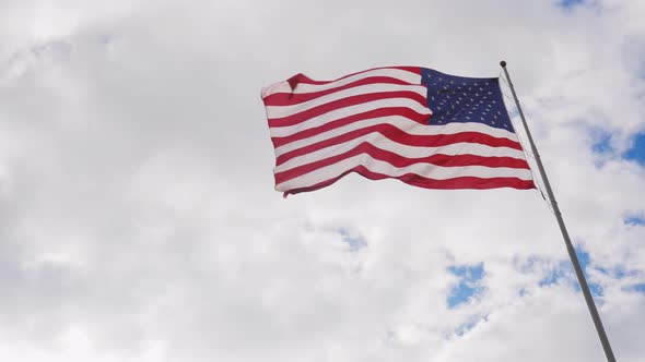 Large US Flag on a Background of Gray Sky Beautifully Illuminated By the Sun alt