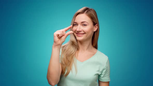 Disappointed Young Woman Showing Small Size Gesture Against Blue Background alt