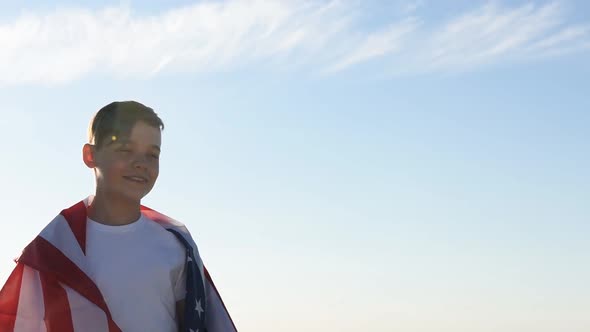 Boy Waving National USA Flag Outdoors Over Blue Sky at the River Bank