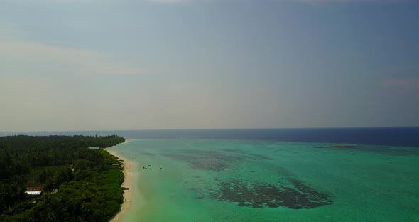 Daytime aerial clean view of a sandy white paradise beach and turquoise sea background in 4K alt