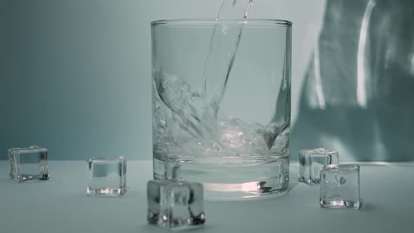 Pour Drinking Water, Mineral Water With Crystal Cubes Into A Glass. alt