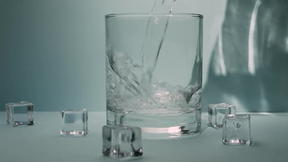 Pour Drinking Water, Mineral Water With Crystal Cubes Into A Glass.