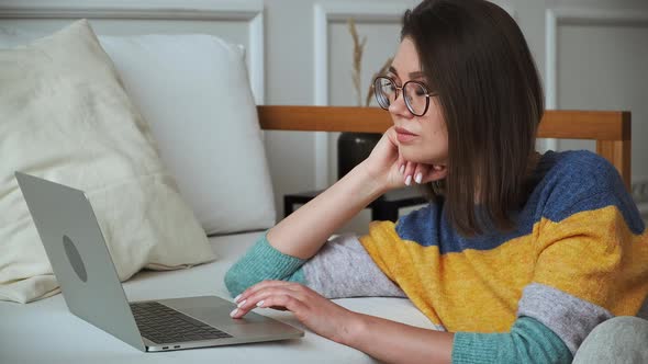 Young Woman Using Laptop Using Touchpad Sitting on the Floor Near the Sofa at Home Remote Work Work alt