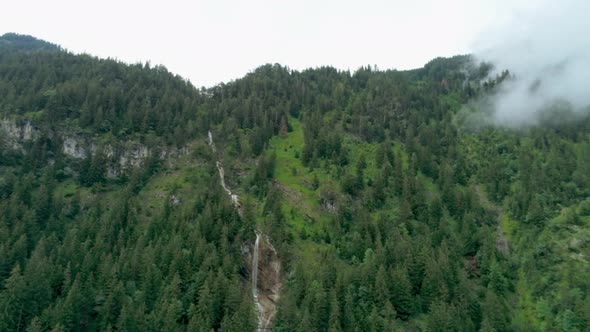 Scenic Aerial View of Waterfall in Mountains with Steaming Forest in German Alps