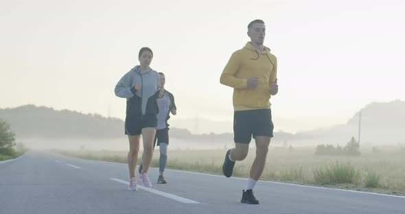 Multiethnic Group of Athletes Running Together on a Panoramic Countryside Road alt