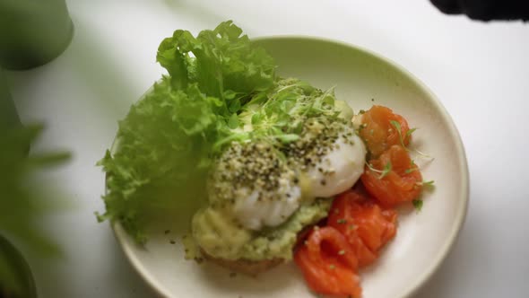 Cook Garnishes Guacamole and Poached Eggs Toast with Greenery alt