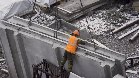 The Builder Works at the Construction Site of the House - He Hooks the Concrete Slab with Chains alt