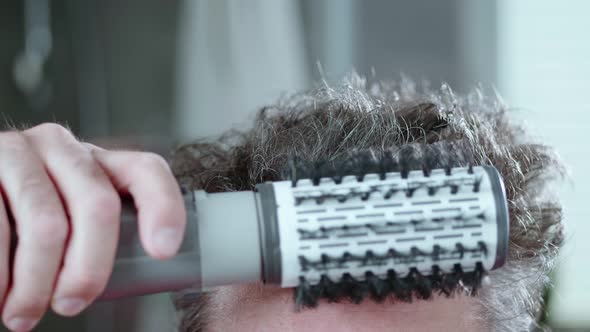 The man is drying his crazy hair, thinning hair