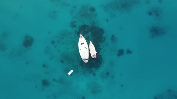Aerial top view of yacht moored in the middle of turquoise crystal clear ocean