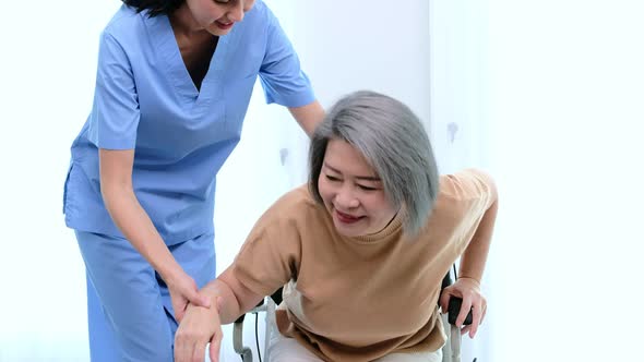 A young Asian nurse take care a disability senior while she sitting on a wheel chair.