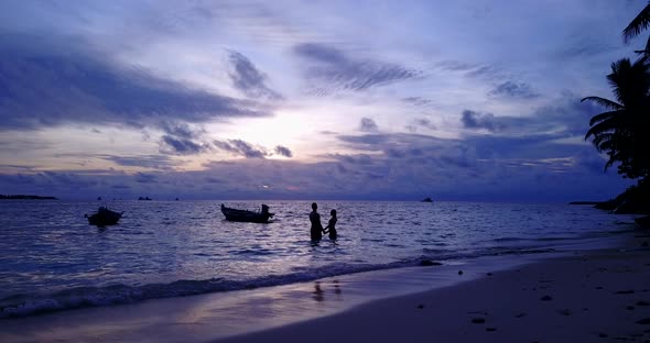 Happy boy and girl on romantic honeymoon have fun on beach on white sand 4K background alt