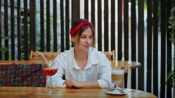 Happy Girl in Cafe Chooses What to Drink Coffee or Cocktail alt