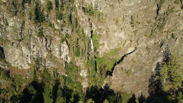 Aerial jib up of Corbata Blanca waterfall flowing between steep mountains with cypress trees, Patago alt