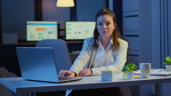 Business Woman Looking at Camera Smiling After Typing on Laptop alt