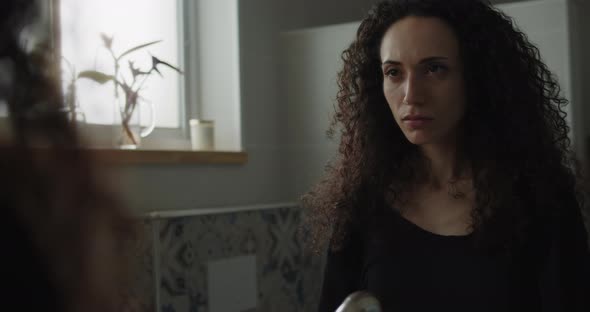 A curly haired woman looking at herself alt