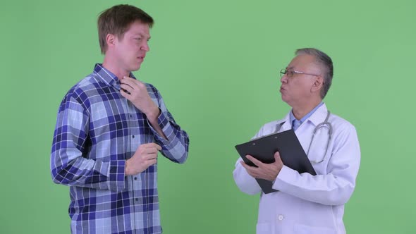 Mature Japanese Man Doctor with Young Man Having Consultation for Sore Throat alt
