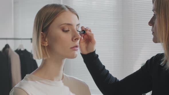 Female Make-Up Artist Putting Mascara on Model alt