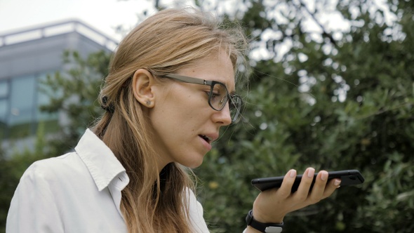 Woman Wearing Glasses Using a Smart Phone Voice Recognition alt