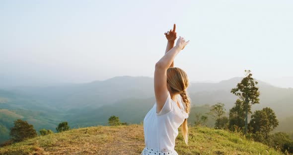 Happy Blond Woman Throw Hands Up and Spinning Around on the Hill in Mountains