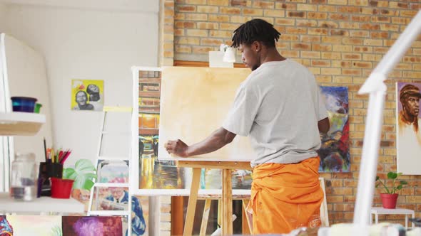 African american male painter painting on canvas in artist studio alt
