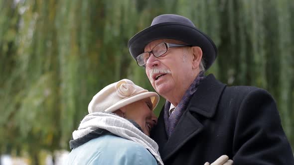 Old European man and woman dancing together in park standing. alt
