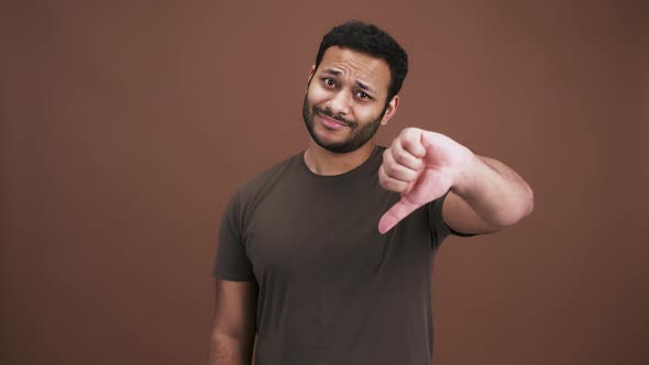 Unhappy Indian Guy Gesturing Thumbs Up with Both Hands Expressing Disapproval Brown Studio alt