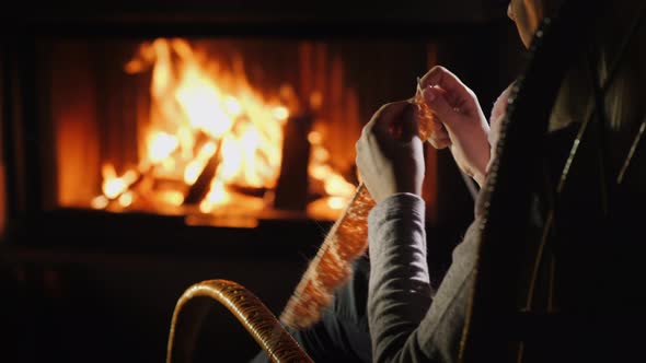 Female Hands with Knitting Needles - Knits Warm Clothes Sitting By the Fireplace alt