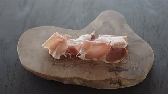 Man Hand Take Prosciutto on Olive Wood Board alt