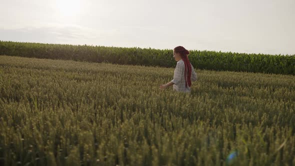 Side View of a Pretty Girl That Walks on a Wheat and Take Photos alt