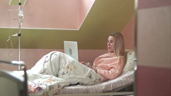 Young Woman Using Laptop Having Video Chat on Hospital Bed alt