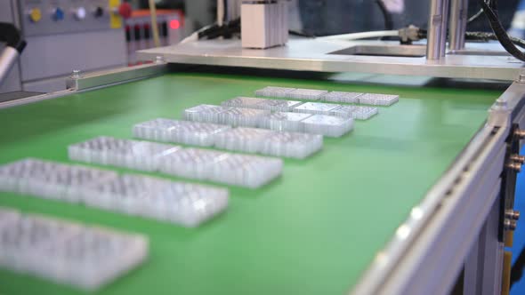 The Automatic Arm of the Robot Spreads Plastic Products on the Conveyor