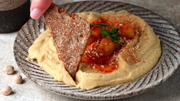Eating hummus with crispbread. hummus with sesame, olive oil and paprika. Healthy vegan food