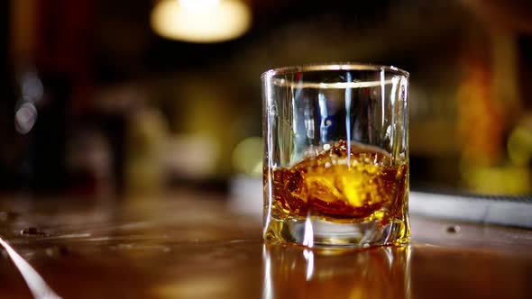 A Professional Bartender is Preparing an Alcoholic Cocktail with Ice Cubes to Customers at the Bar alt