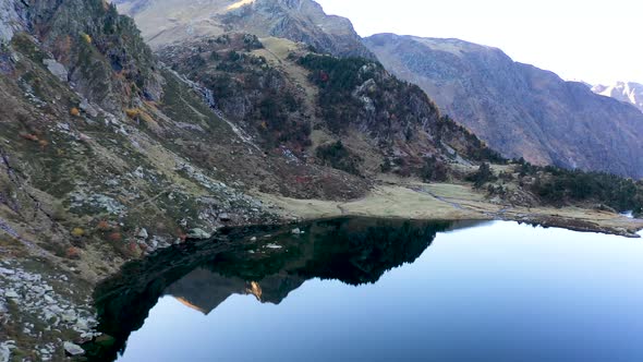 Lac d'Espingo reflecting mountain lake located in Haute-Garonne, Pyrénées, France, Aerial flyover pa alt